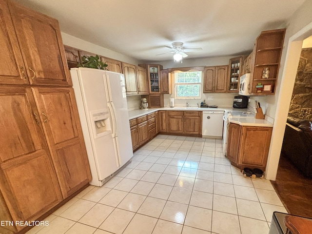 kitchen featuring white appliances, a ceiling fan, brown cabinetry, light countertops, and glass insert cabinets