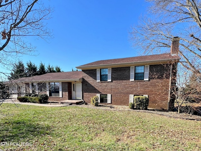 split level home featuring a front lawn, brick siding, and a chimney