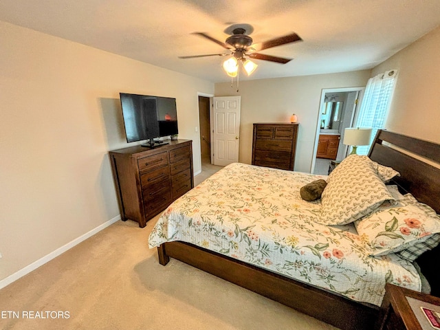 bedroom with baseboards, light colored carpet, ensuite bathroom, and a ceiling fan