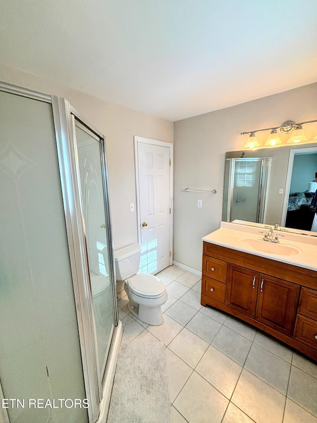 bathroom featuring toilet, a stall shower, tile patterned flooring, baseboards, and vanity