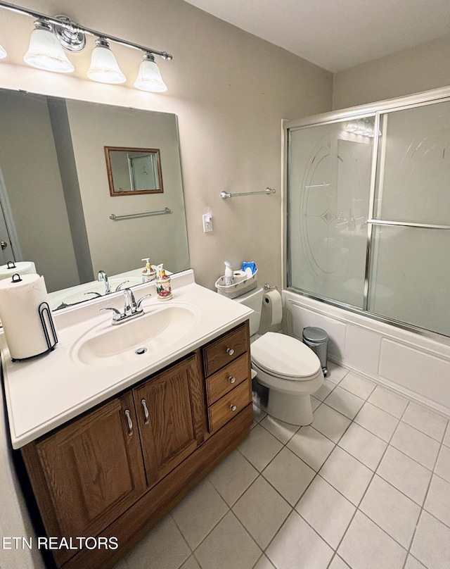 full bathroom with bath / shower combo with glass door, toilet, vanity, and tile patterned flooring