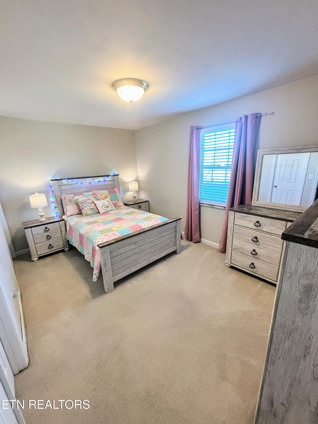 bedroom with baseboards and light colored carpet