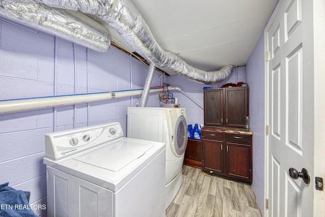 washroom featuring light wood finished floors, laundry area, independent washer and dryer, and concrete block wall