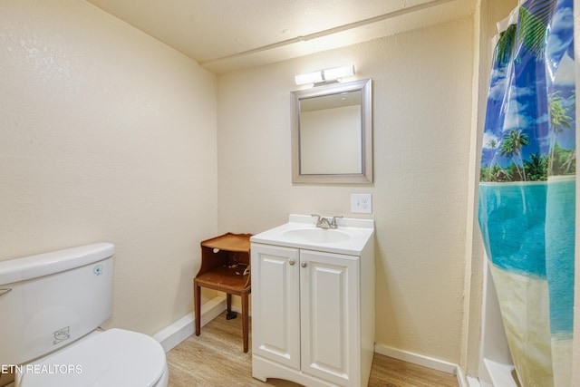 full bath with baseboards, toilet, wood finished floors, and vanity