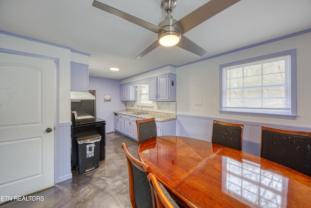 dining space with a wainscoted wall and ceiling fan