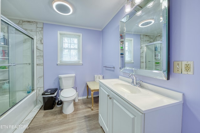 bathroom with crown molding, toilet, wood finished floors, combined bath / shower with glass door, and vanity