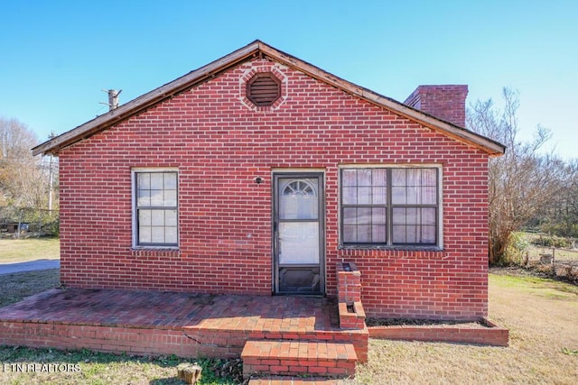 bungalow with brick siding and a chimney