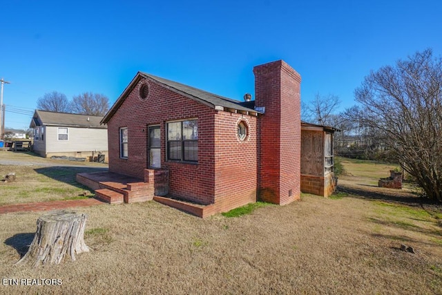 view of side of home featuring a yard, brick siding, and a chimney