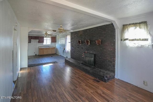 unfurnished living room with a sink, a textured ceiling, wood finished floors, and a ceiling fan