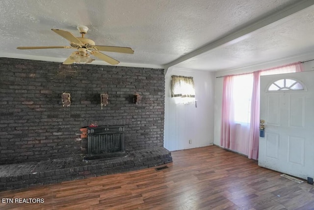 foyer with a fireplace, wood finished floors, visible vents, and a textured ceiling