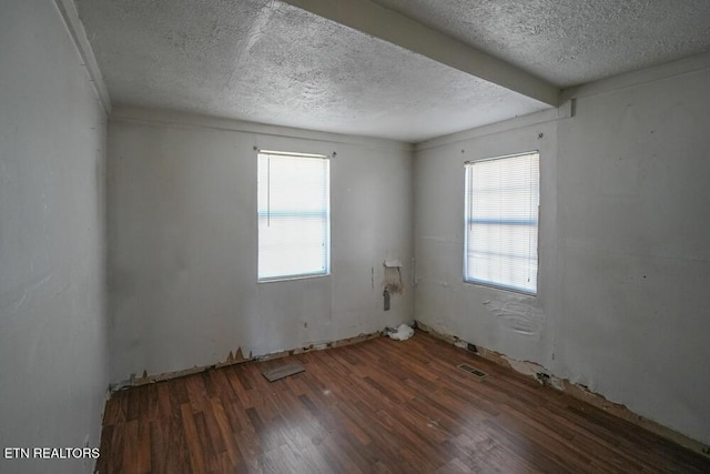 spare room featuring visible vents, a textured ceiling, and wood finished floors