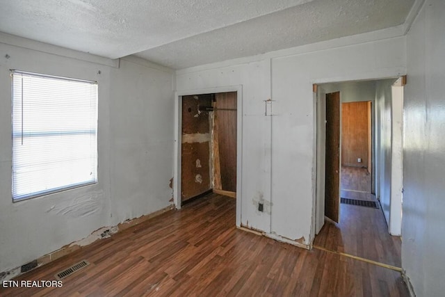 unfurnished bedroom featuring visible vents, a textured ceiling, and wood finished floors