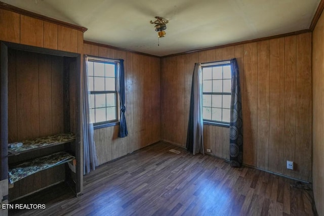 spare room featuring wood finished floors, wood walls, and ornamental molding