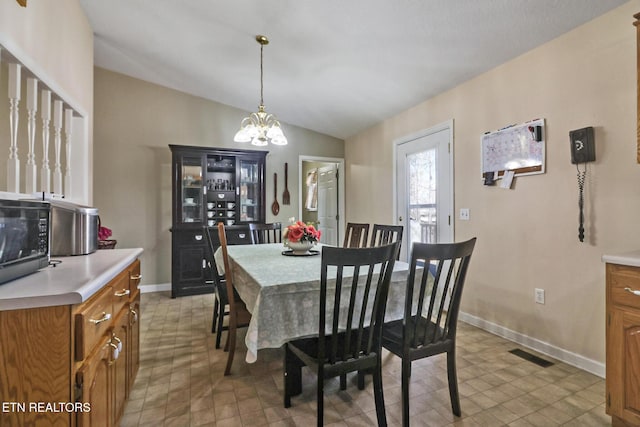 dining area with visible vents, baseboards, an inviting chandelier, and vaulted ceiling