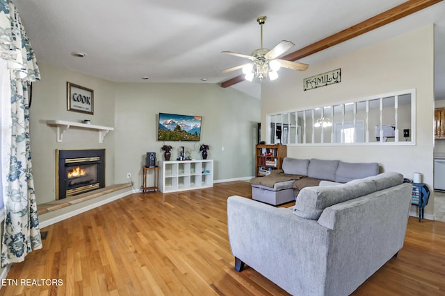 living area featuring a glass covered fireplace, ceiling fan, and wood finished floors