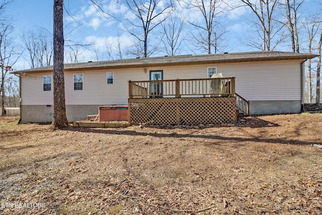back of property with crawl space, a hot tub, and a deck