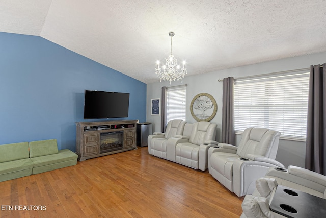 living area featuring lofted ceiling, an inviting chandelier, light wood finished floors, and a textured ceiling