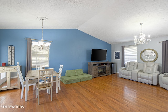 dining room featuring a textured ceiling, lofted ceiling, an inviting chandelier, and hardwood / wood-style floors