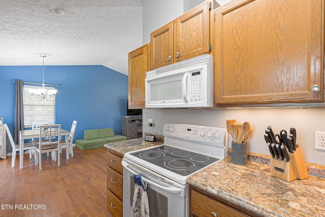 kitchen featuring white appliances, wood finished floors, vaulted ceiling, a textured ceiling, and a chandelier