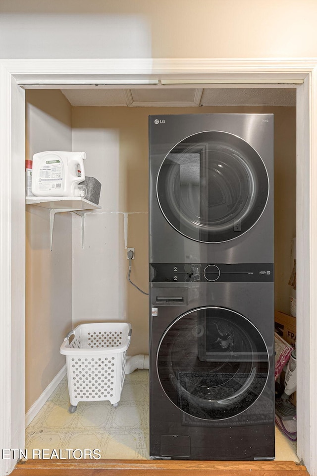 clothes washing area featuring stacked washer / drying machine and baseboards