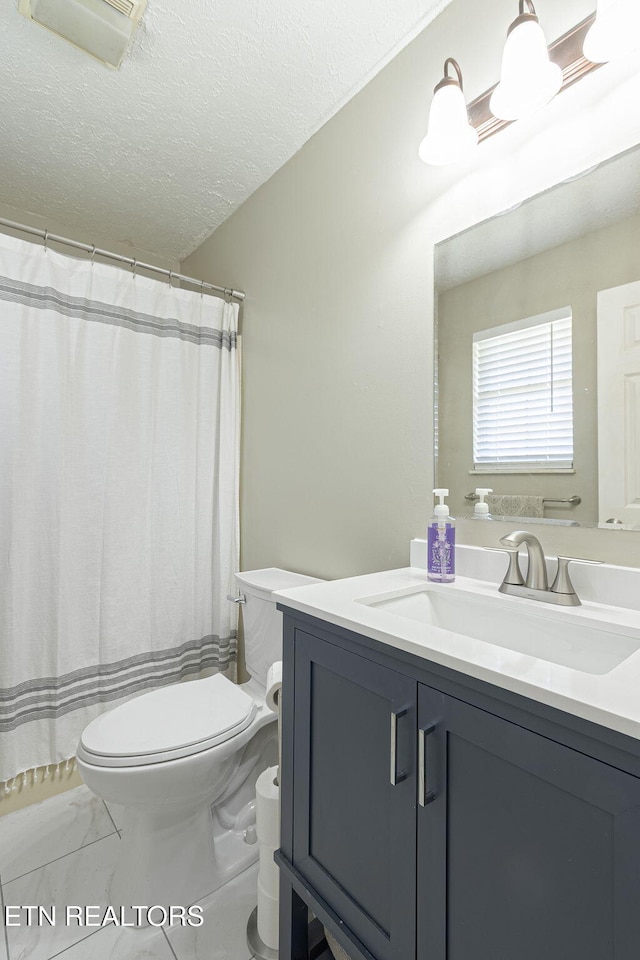 full bathroom featuring vanity, toilet, marble finish floor, and a textured ceiling