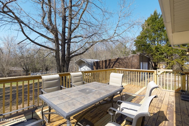 wooden deck featuring outdoor dining area and an outbuilding