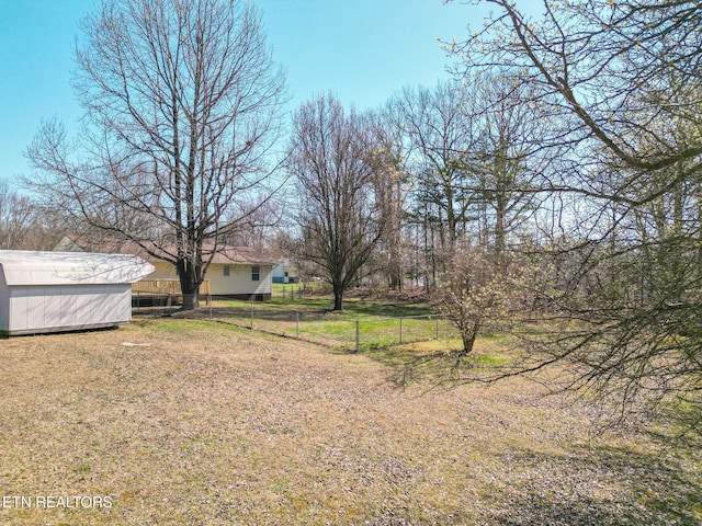 view of yard featuring an outbuilding, fence, and a shed