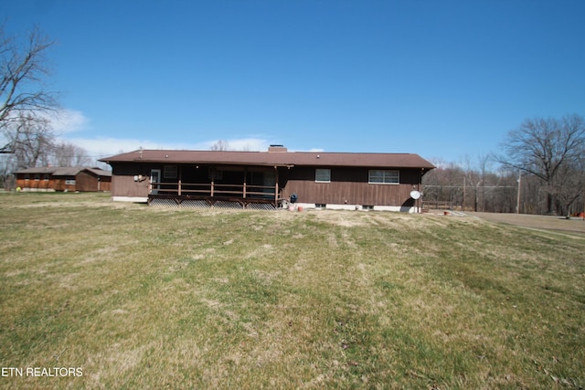 rear view of property with a wooden deck and a lawn