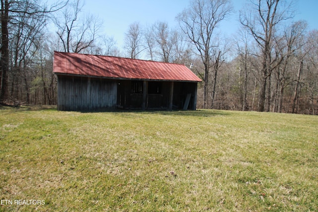 view of pole building featuring a lawn and a view of trees