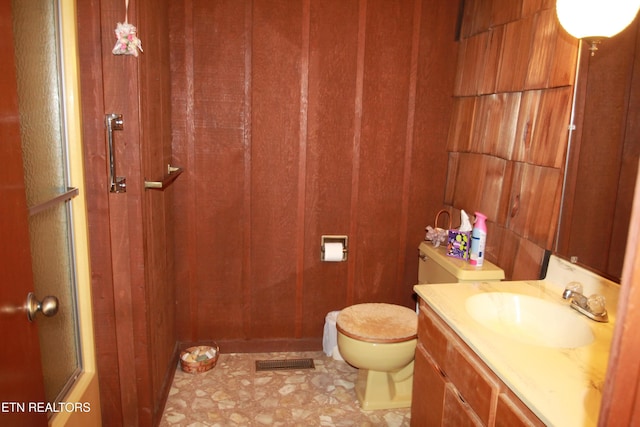 full bath with vanity, wooden walls, visible vents, an enclosed shower, and toilet