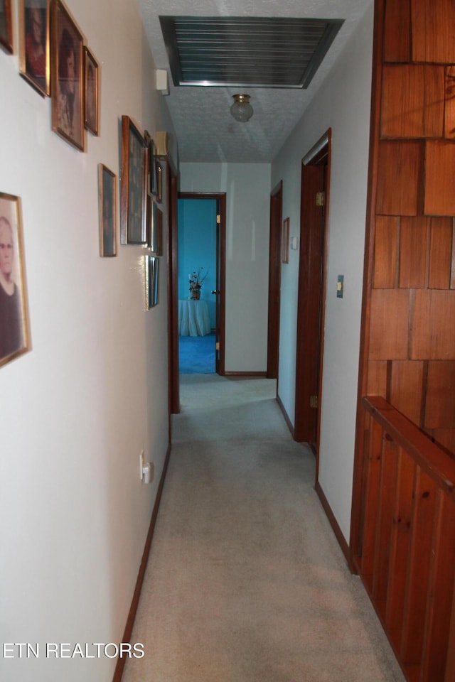 hallway featuring visible vents, light colored carpet, and baseboards