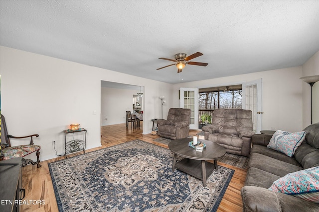 living area with a textured ceiling, wood finished floors, and ceiling fan