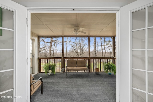 unfurnished sunroom with wood ceiling and a ceiling fan