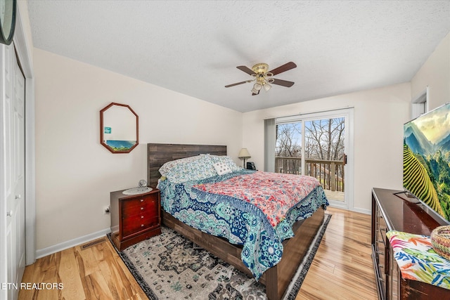 bedroom featuring baseboards, light wood-style floors, and a textured ceiling