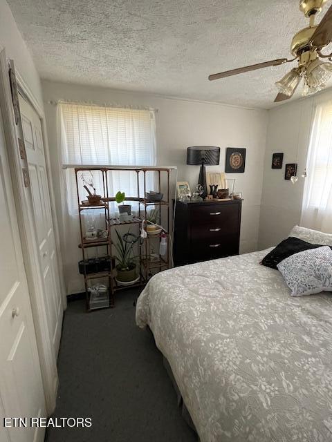 carpeted bedroom with ceiling fan and a textured ceiling