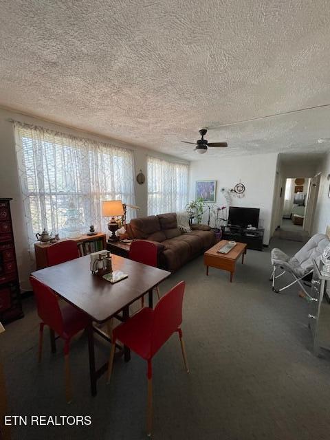 dining space featuring a textured ceiling, carpet flooring, and ceiling fan