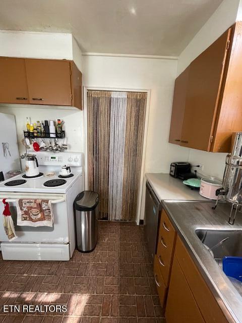 kitchen featuring brown cabinetry, brick patterned floor, and white range with electric cooktop