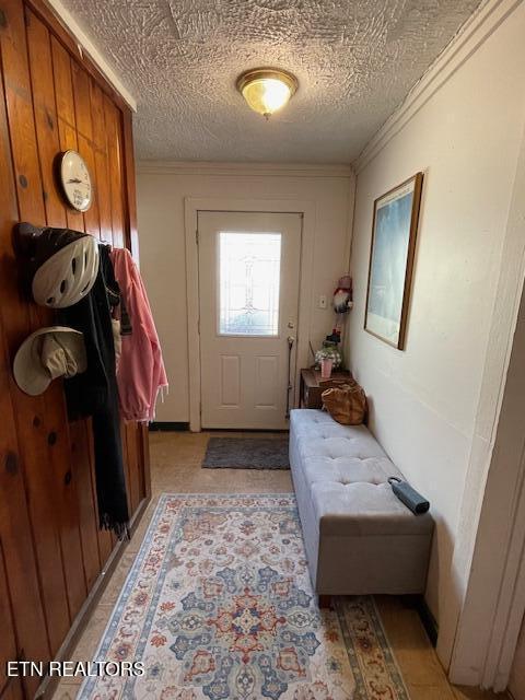 entryway featuring a textured ceiling and crown molding