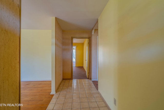 hall with light tile patterned flooring and baseboards