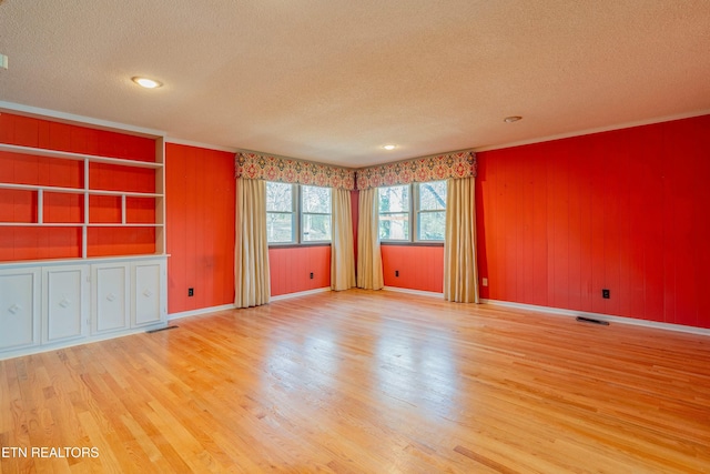 spare room with baseboards, wood finished floors, visible vents, and a textured ceiling