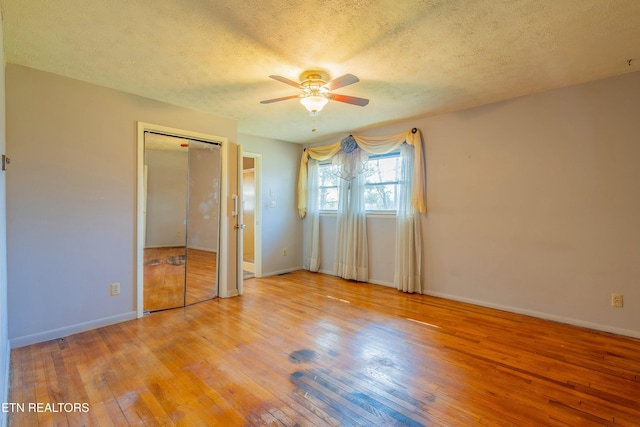 unfurnished bedroom with a textured ceiling, a ceiling fan, baseboards, and hardwood / wood-style floors