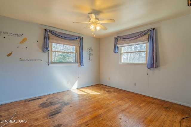 unfurnished room with visible vents, baseboards, ceiling fan, and hardwood / wood-style flooring