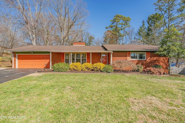 ranch-style house featuring a front yard, a chimney, a garage, aphalt driveway, and brick siding