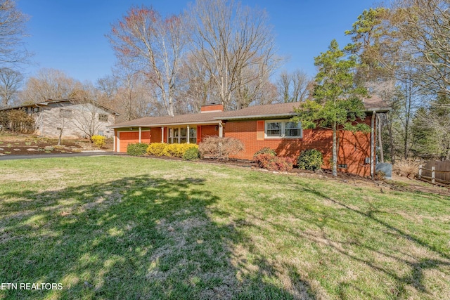 view of front of house with a front yard, driveway, a chimney, a garage, and brick siding