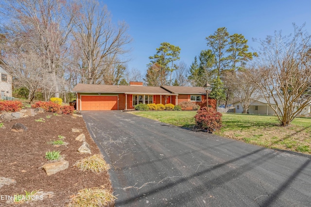 single story home featuring a front yard, an attached garage, and driveway