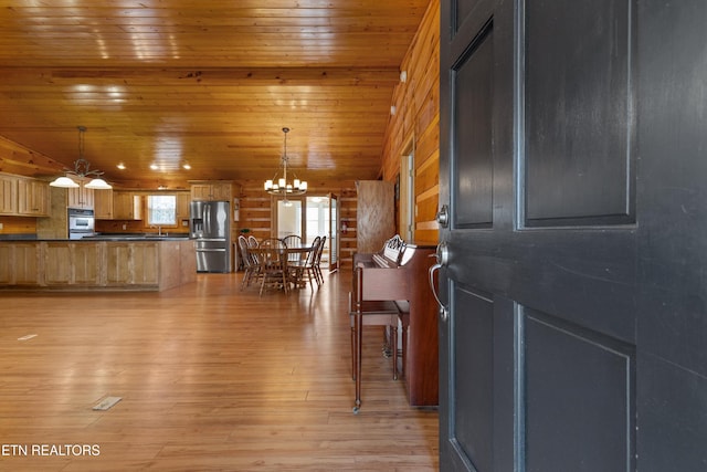 interior space with dark countertops, a chandelier, light wood-type flooring, wooden ceiling, and stainless steel refrigerator with ice dispenser