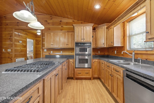 kitchen with dark countertops, light wood finished floors, a sink, stainless steel appliances, and wooden ceiling