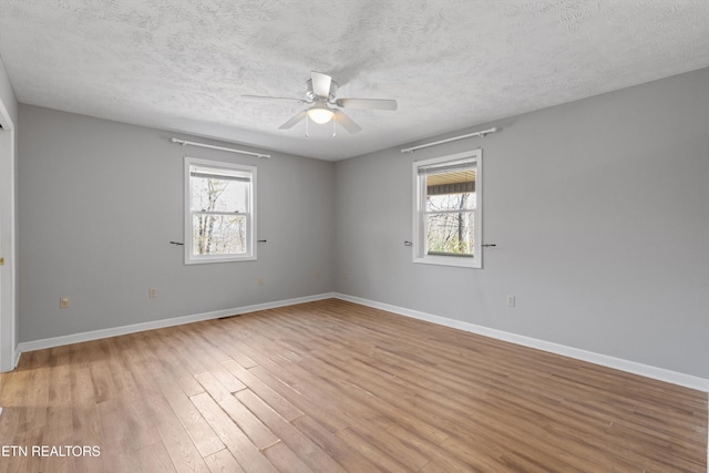 unfurnished room with plenty of natural light, baseboards, light wood finished floors, and ceiling fan