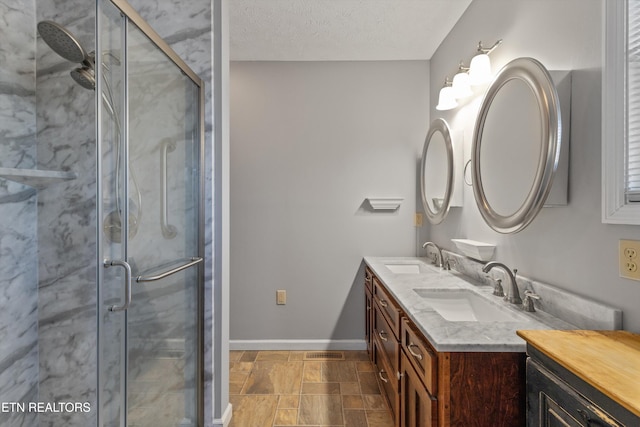 bathroom with a sink, baseboards, double vanity, and a shower stall