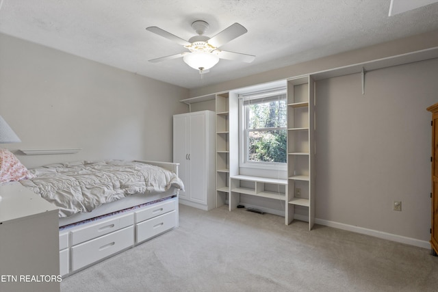 bedroom with a textured ceiling, a ceiling fan, baseboards, and light carpet